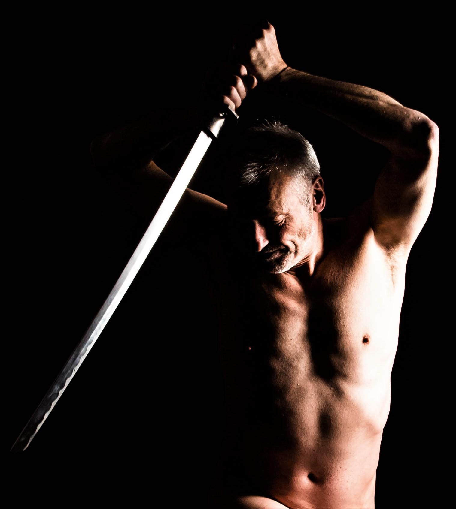 life model Julian, posing with a sword in dramatic light for an artist to draw or sculpt
