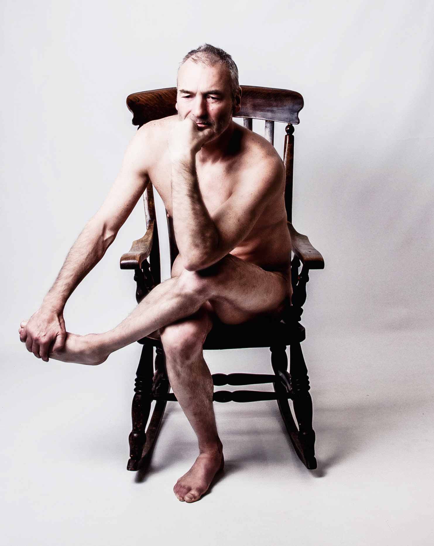 life model Julian, sat on a wooden chair for an artist to draw or sculpt